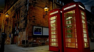 red telephone booth in front of brown brick building