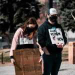 woman in black and white long sleeve shirt holding brown cardboard box