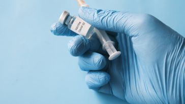 person in white gloves holding white plastic bottle